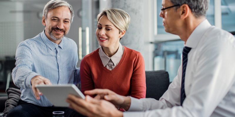 happy-mid-adult-couple-using-touchpad-with-their-financial-consultant-in-the-office-.jpg